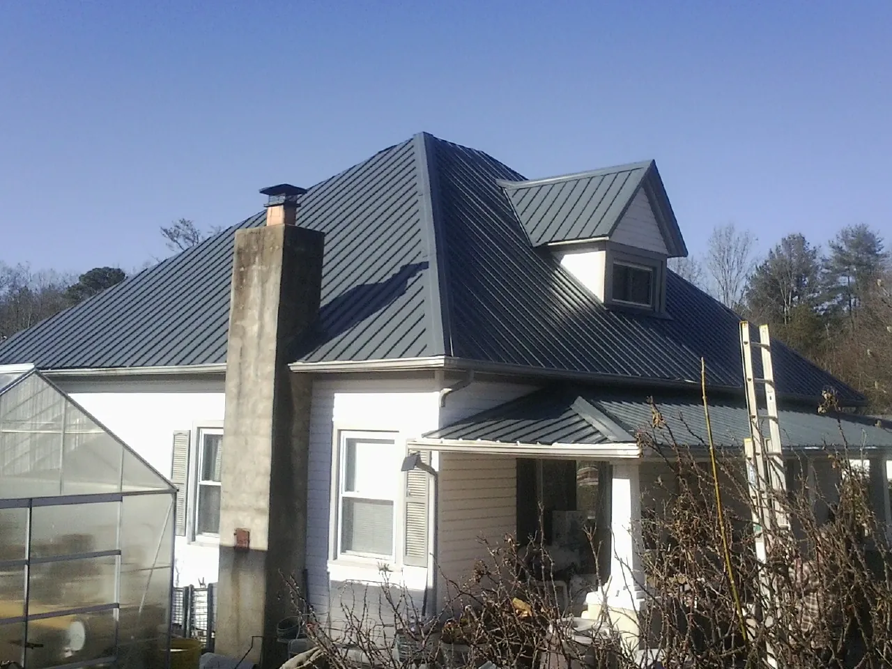 Dark blue standing seam metal roof on a white farmhouse with dormer — Slate & Tile Roof Repair by Roofing Brothers in Calumet City