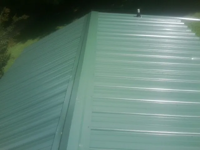 New green metal panels meeting at the ridge of a roof — Flat Roof Repair work by our crew in Calumet City