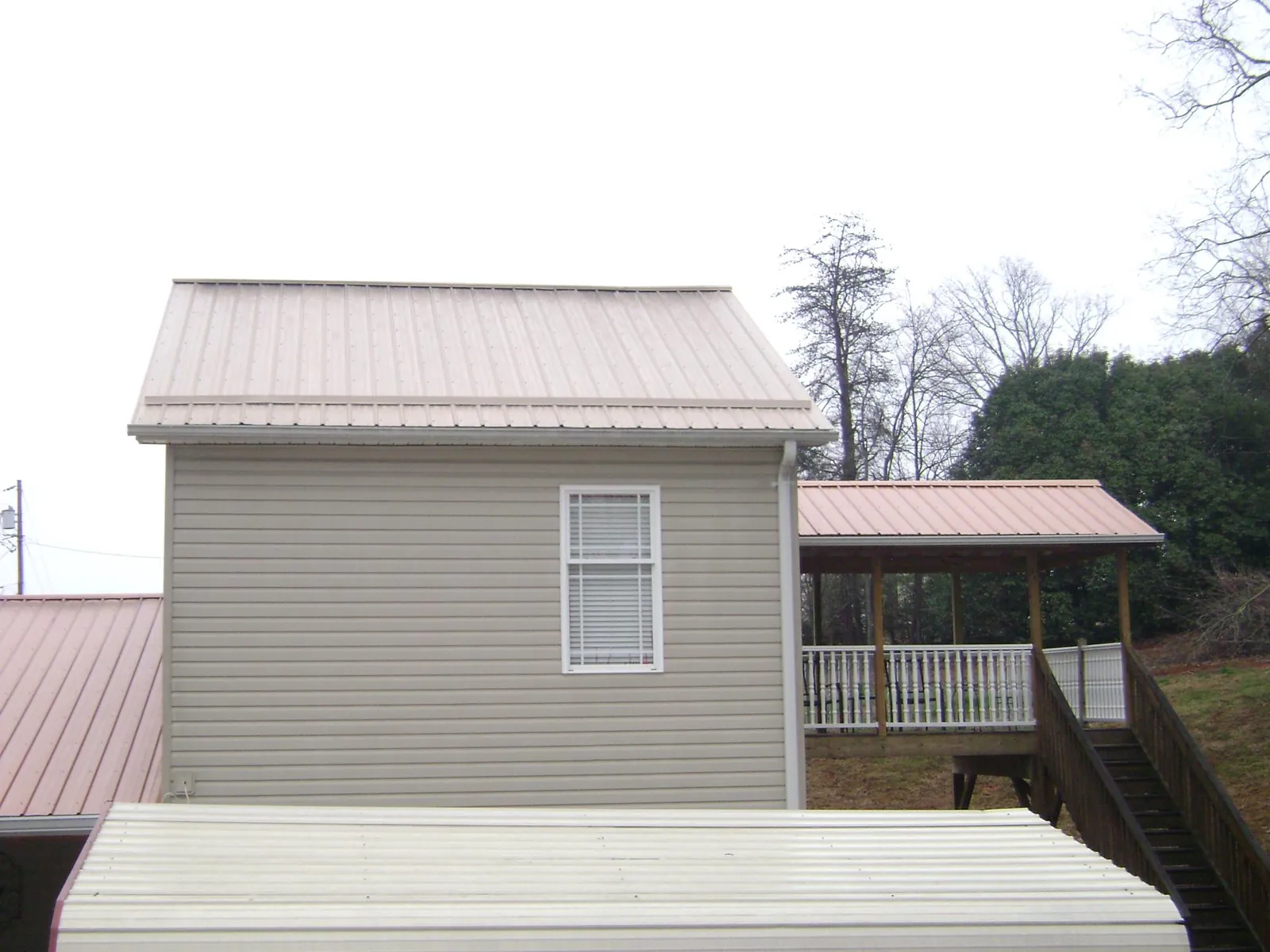 Tan metal roofs on a two story addition and attached porch, from a Roof Replacement job in Calumet City