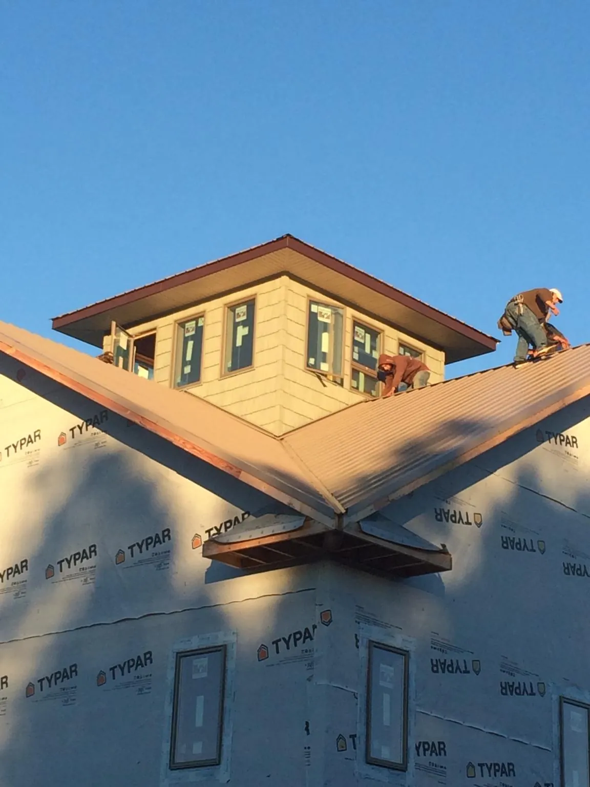 Roofers working around a rooftop cupola on a new metal roof at sunset — Roof Waterproofing in Calumet City by Roofing Brothers